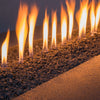 A close-up of extra small volcanic lava rocks, focusing on their textured and porous surface. The black lava rocks are arranged inside a fire feature, providing a natural and rugged aesthetic to any outdoor space. Their durable material makes them ideal for retaining heat and enhancing the glow of any fire pit or fireplace.