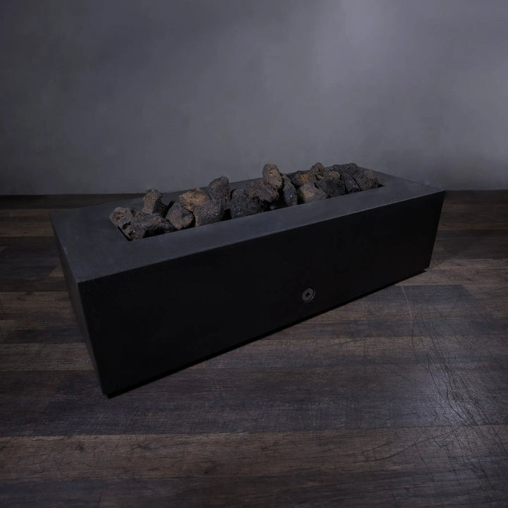 Outdoor volcanic lava rock set in a rectangular fire pit. The large, dark-toned lava rocks create a rustic yet modern fire pit look, perfectly suitable for outdoor use. The image showcases the lava rocks without the fire, highlighting their textured surface and natural appearance. These large volcanic stones are ideal for adding both style and functionality to fire pits, providing a durable, heat-resistant layer that improves air circulation and adds a natural charm to any fire feature