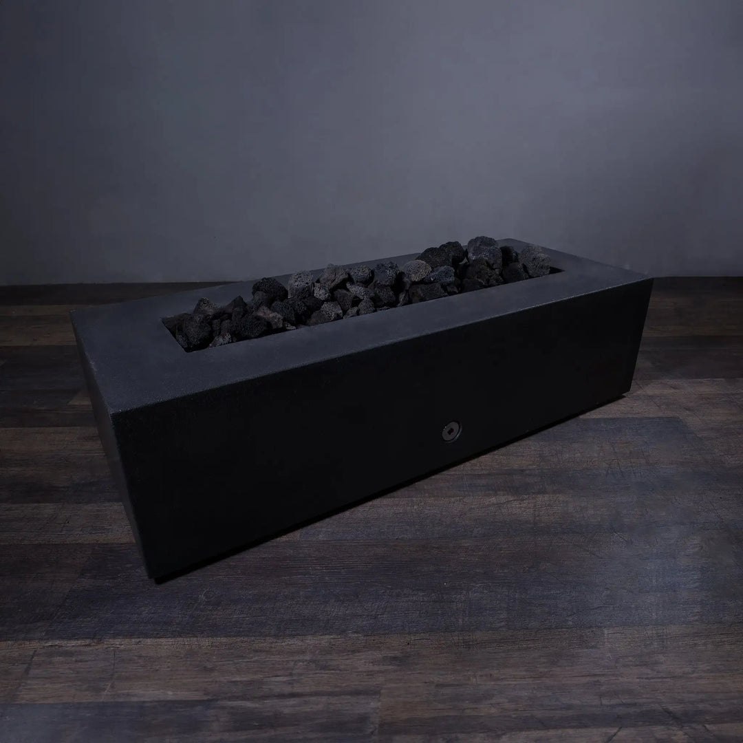 Medium volcanic lava rocks resting in a modern fire pit without flames. The 2-3 inch black porous stones are perfect for retaining heat and maintaining a rugged, natural outdoor aesthetic. Ideal for use in fire pits and outdoor fireplaces