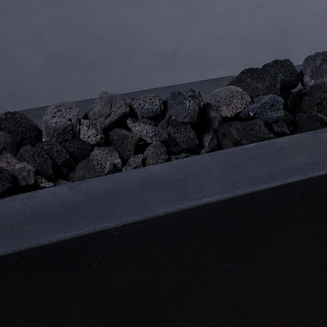 Close-up of medium volcanic lava rocks without flames in a fire pit. These 2-3 inch porous stones are perfect for fire pits, offering durability, superior heat retention, and a visually appealing natural texture.