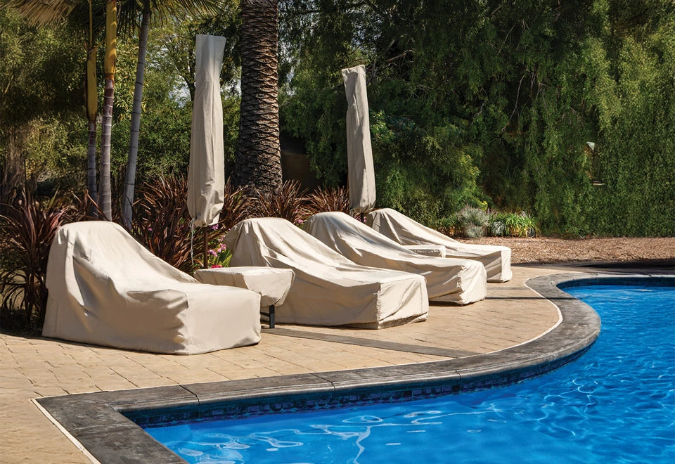 Beige protective covers on poolside chaise lounges and umbrellas, providing weather-resistant protection against the elements in a lush outdoor setting.