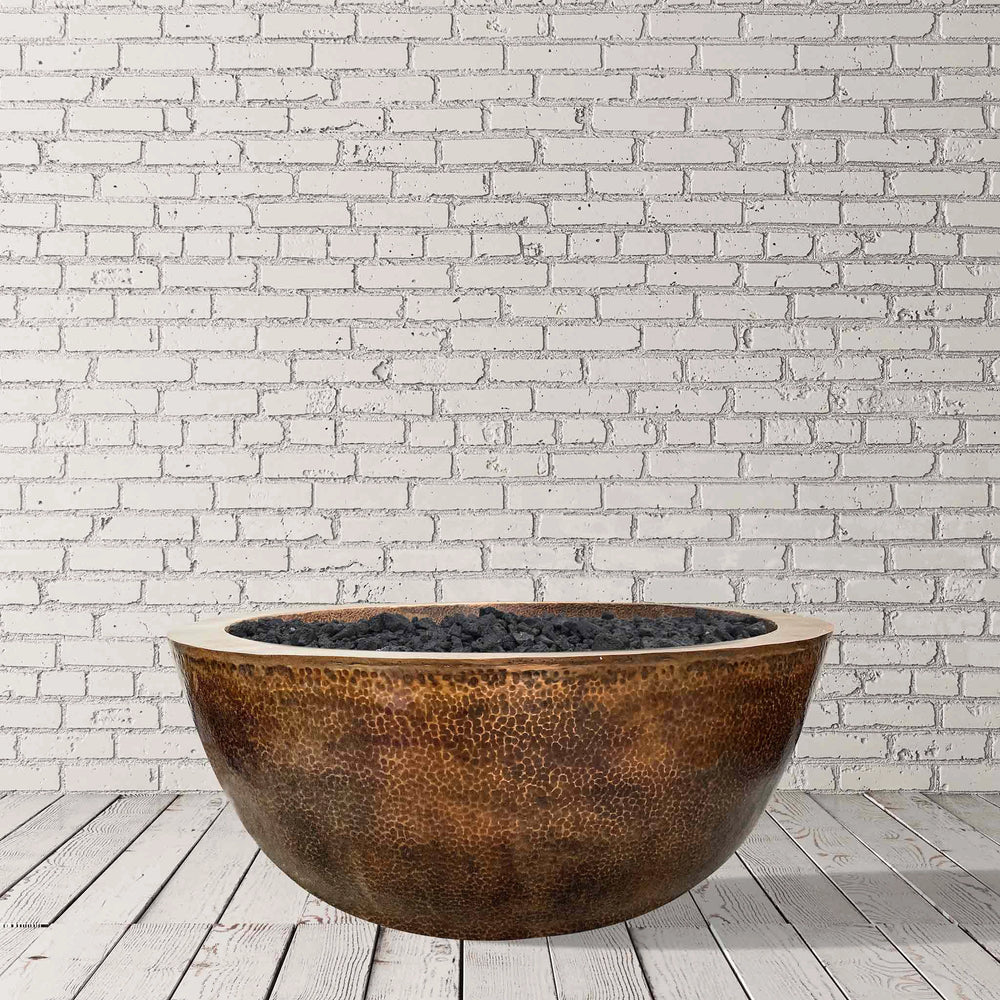 A studio view of the Prism Hardscapes 39" Edel Hospitality Moderno 1 Copper Fire Bowl against a minimalist white brick backdrop. This high-end fire pit is made from premium copper with a hammered finish, perfect for modern outdoor spaces. 