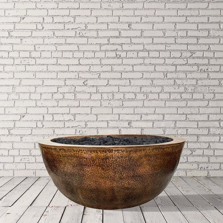 A studio view of the Prism Hardscapes 39" Edel Hospitality Moderno 1 Copper Fire Bowl against a minimalist white brick backdrop. This high-end fire pit is made from premium copper with a hammered finish, perfect for modern outdoor spaces. 