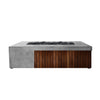 Prism Hardscapes Fairmont Fire Table in pewter concrete, complemented by natural wood paneling and dark lava rocks on top. This fire table offers a stylish yet functional fire pit solution, perfect for modern outdoor spaces. 