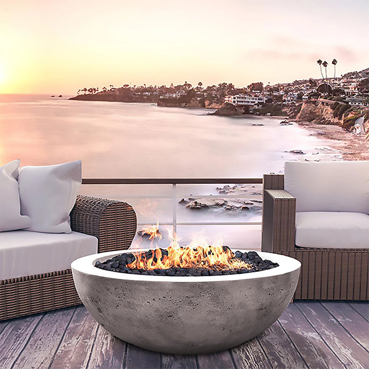 Breathtaking ocean view with the Prism Hardscapes Moderno 4 Gas Fire Pit in a natural concrete finish. The fire bowl provides warmth and ambiance as it enhances the coastal outdoor space, perfect for relaxing by the sea. This fire pit can be used with natural gas or propane."