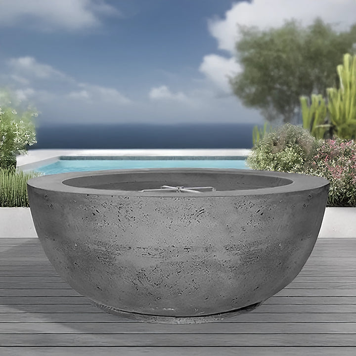 The Prism Hardscapes Moderno 8 Gas Fire Pit in Pewter displayed in a luxurious poolside setting, showcasing its modern design and sturdy construction. This round concrete fire bowl adds a contemporary touch to outdoor spaces, ideal for backyard fire pits, modern gas fire bowls, and large outdoor fire features. Its sleek, weather-resistant finish makes it perfect for patios or poolside settings, blending seamlessly with the surrounding decor.