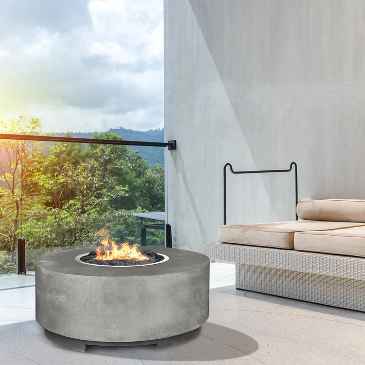 The Prism Hardscapes Rotondo Gas Fire Pit in Natural graces this modern outdoor terrace with a sophisticated, minimalist design. Made from durable concrete and finished in natural gray, it complements sleek furniture and contemporary settings. This fire pit, powered by natural gas, includes lava rocks, perfect for outdoor patios, rooftop terraces, and modern backyard designs. Its round design adds warmth and style to any outdoor gathering space.