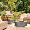 The Prism Hardscapes Rotondo Gas Fire Pit in Natural provides a sleek, round centerpiece to this cozy patio setup. Paired with a natural chair and modern furniture, it complements the outdoor living space beautifully. This concrete fire pit is ideal for creating warmth in outdoor spaces, backyard designs, and modern patios. It operates on natural gas and includes lava rocks for a balanced mix of style and function, perfect for outdoor fire pit settings, modern fire pits, and outdoor gatherings.