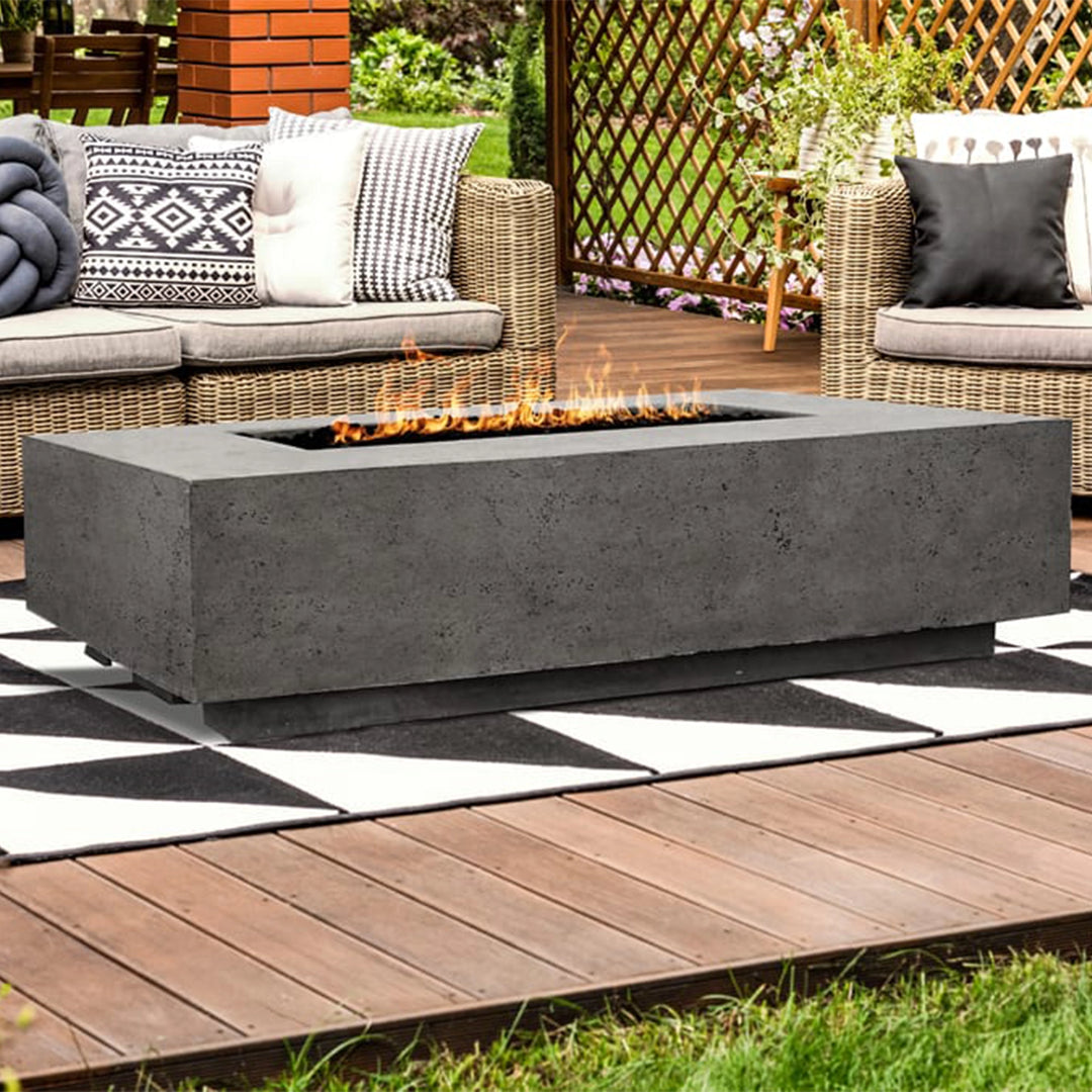 Prism Hardscapes Tavola 1 Gas Fire Pit in natural gray, beautifully integrated into a modern backyard deck setting. Surrounded by comfortable seating and outdoor décor, the fire pit adds an element of luxury and warmth. Its sleek, rectangular design offers a large fire feature, perfect for entertaining on cool evenings.