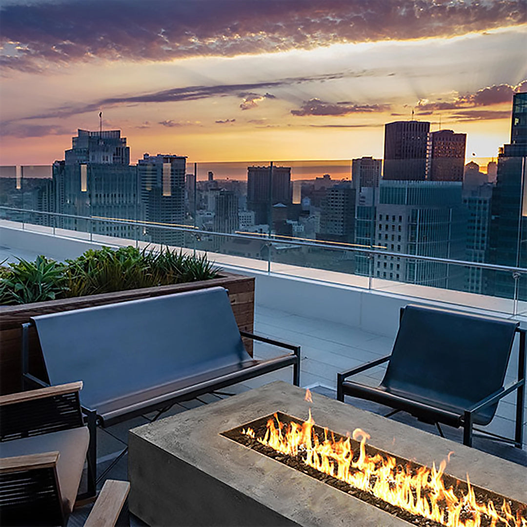 A modern patio setup featuring the Prism Hardscapes Tavola 6 Gas Fire Pit, flanked by stylish woven chairs. The concrete fire pit blends seamlessly with the sleek, contemporary decor, offering both warmth and sophistication for outdoor entertaining. Ideal for residential or commercial patios