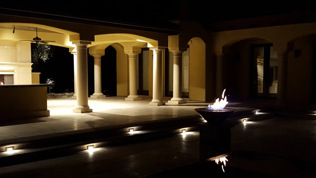a fire bowl near a bowl is ignited at night to accent the pool nearby.