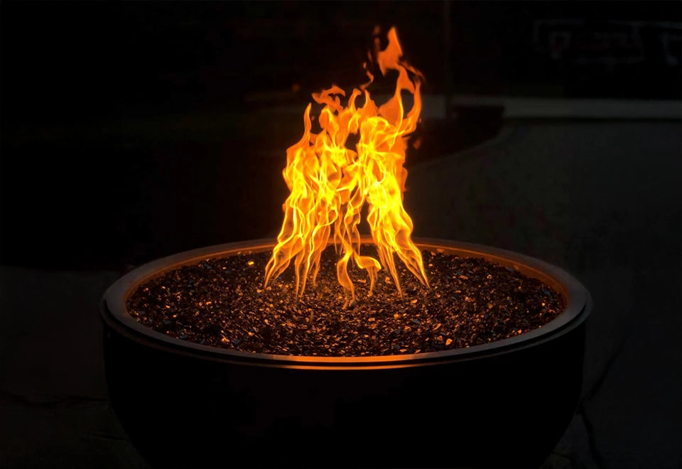 Modern round black gas fire pit with vibrant flames and reflective black fire glass media, featuring a convenient push-button ignition system. Ideal for enhancing backyard settings with warmth and ambiance, perfect for contemporary outdoor fire pit installations.