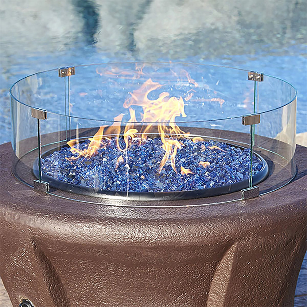 This image features the Round Glass Flame Guard by American Fireglass, elegantly placed poolside. The flame guard surrounds vibrant blue fire glass with a flickering flame, providing protection and enhancing the fire pit’s appearance. Perfect for outdoor fire pits, this round tempered glass guard offers both style and safety by shielding the fire from wind. Ideal for enhancing fire pit aesthetics and functionality.