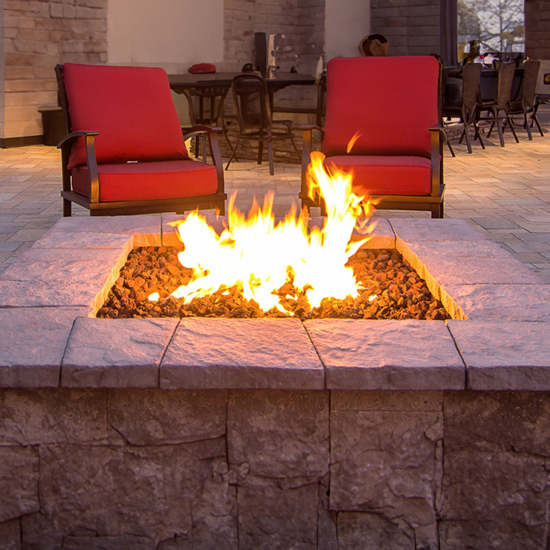 Lifestyle image showcasing the square stainless steel fire ring by HPC Fire in use within a custom-built outdoor fire pit. This image highlights the beautiful flame pattern and even heat distribution of the 36-inch fire ring, creating a cozy and welcoming atmosphere. Surrounded by natural stone, the fire pit is the focal point of the outdoor space, perfect for gatherings and entertaining. The stainless steel fire ring is designed for durability and longevity, ensuring a vibrant and consistent flame. 