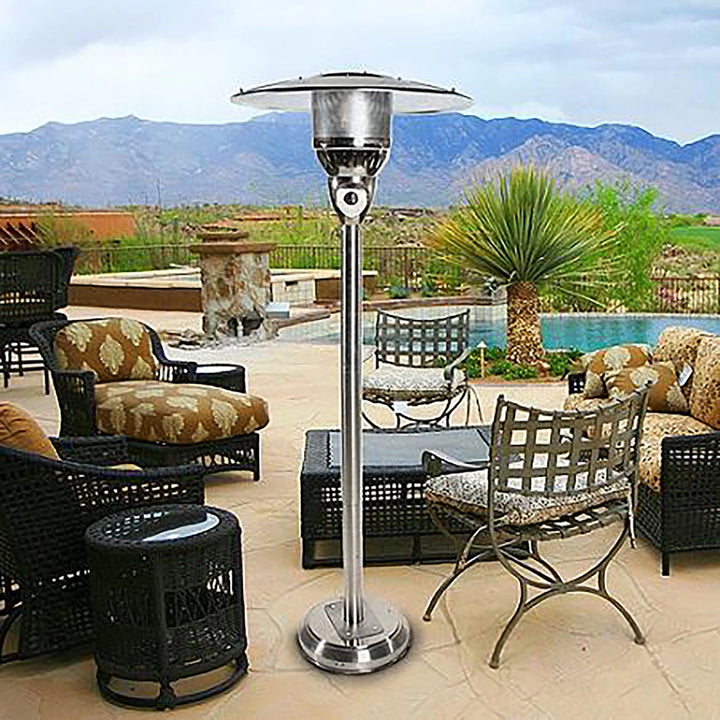 A stainless steel natural gas patio heater set in an outdoor patio area with a scenic mountain backdrop. The patio heater is positioned beside stylish outdoor furniture, providing ample heat for comfort during cool evenings. The modern design and durable construction make it ideal for upscale outdoor environments.