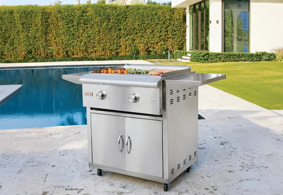 Stainless steel outdoor griddle on a mobile cart, perfect for backyard cooking and grilling by the poolside in a modern outdoor setting.