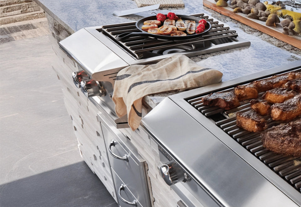 Premium stainless steel outdoor kitchen with side burner and grill, featuring sizzling steaks and grilled vegetables on a granite countertop setting.