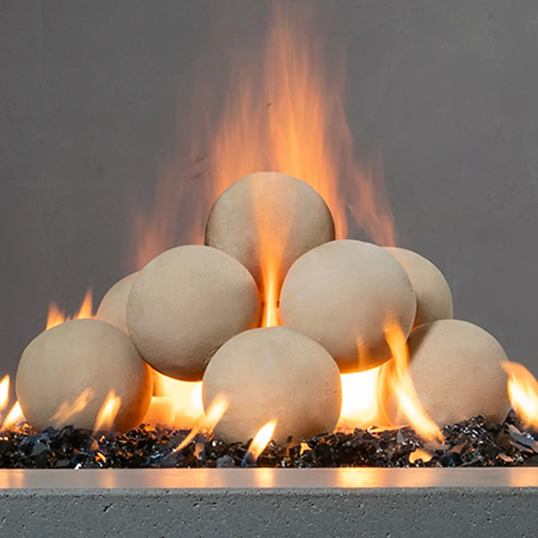 Close-up view of beige Starfire Designs 4-inch ceramic fire balls with flames rising between them. The fire balls' smooth surface and spherical shape provide a modern, clean aesthetic. Perfect for luxury fire pits, these ceramic balls are designed for high heat resistance, adding both style and function to any fire feature