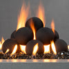 Close-up view of the Starfire Designs 4-inch black ceramic fire balls set of 12 with flames rising between them. The fire balls are arranged atop black reflective fire glass, creating a dynamic and modern look. Perfect for enhancing outdoor fire pits with a sleek, stylish aesthetic