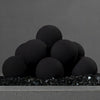 Close-up image of the unlit black ceramic fire balls from Starfire Designs, set of 12. The fire balls are neatly arranged on top of black fire glass, showcasing their smooth matte finish. A perfect choice for outdoor gas fire pits, adding a minimalist yet bold design element