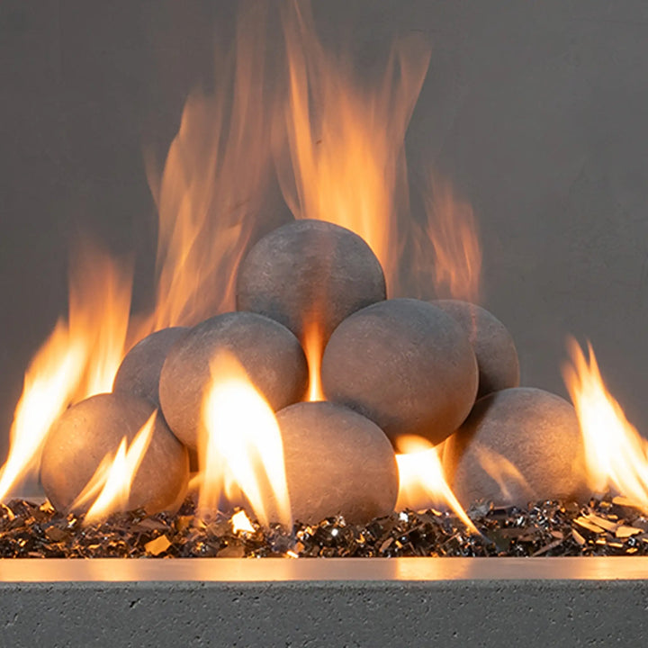 Close-up of Starfire Designs 4-inch ceramic fire balls in light gray, neatly stacked on black glass media. The textured surface and modern design make these fire balls a perfect addition to luxury outdoor fire pits or fireplaces. They are designed to complement a variety of fire media options while maintaining heat resistance