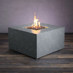 This image displays the Starfire Designs Beton 42" Graphite Square Hidden Propane Tank Gas Fire Pit in action with flames rising from the lava rocks. The modern design in graphite gray complements outdoor patios, providing a stylish and functional heating solution. Featured are the clean, square edges of the fire pit and its weather-resistant concrete construction. Perfect for outdoor gatherings, this fire pit operates using a hidden propane tank system.