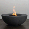 A low, graphite-colored round fire pit with a smooth, sculptural bowl shape sends a steady column of flame upward from a bed of dark lava rocks, the minimalist concrete fire pit resting on a wood-look patio surface and showcasing a clean-lined modern fire pit design, powered by a hidden natural gas fire pit burner that delivers consistent heat and an elegant focal point for contemporary outdoor lounges and compact urban terraces.