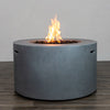 A full view of the Starfire Designs Beton 42" Natural Gray Round Concrete Gas Fire Pit showcasing the impressive flame display rising from the lava rock bed. The simple round concrete design with smooth edges offers a modern focal point for any outdoor space.