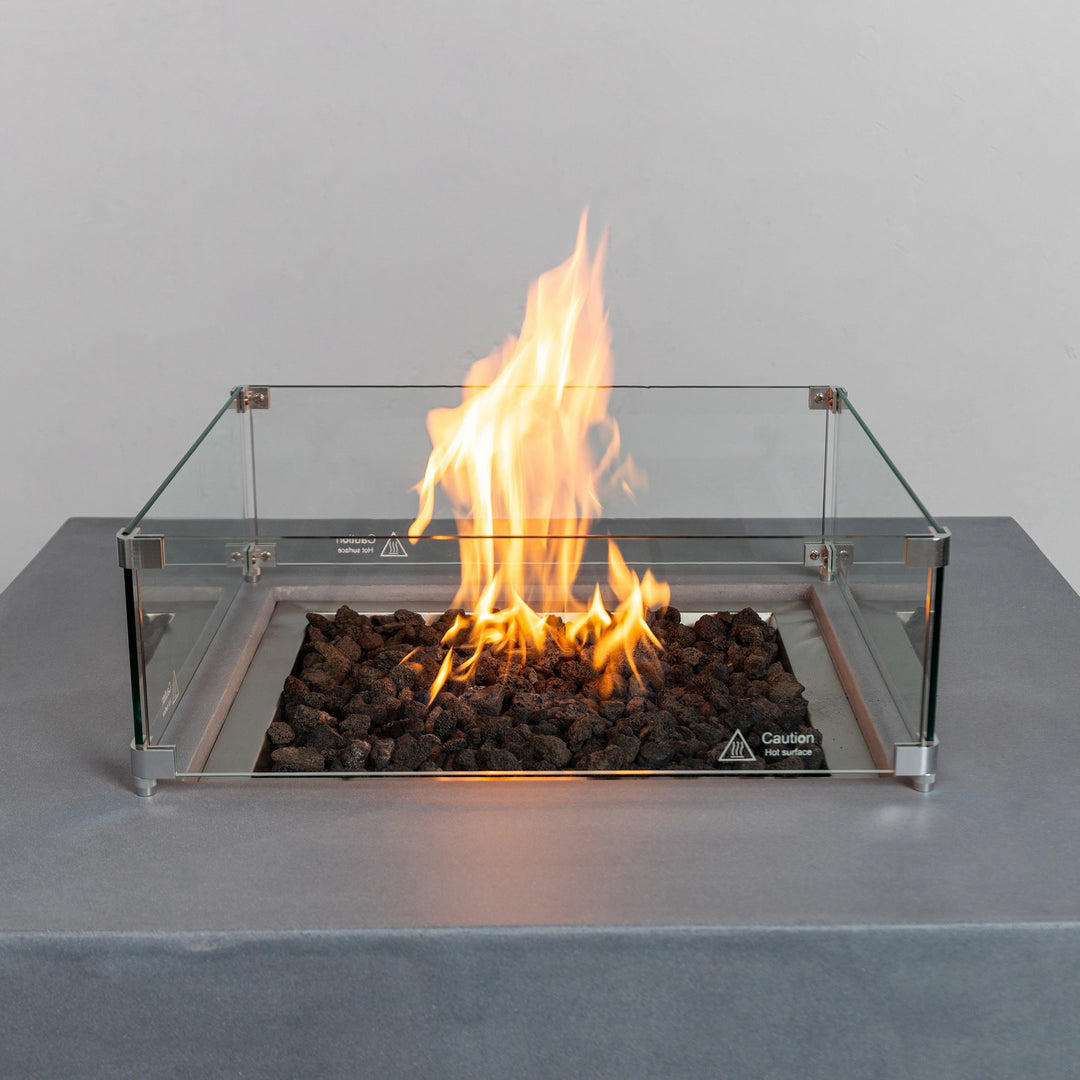  Close-up of the Starfire Designs Beton 42" Natural Gray Square Hidden Propane Tank Gas Fire Pit’s flames surrounded by lava rocks, encapsulated in a glass wind guard. Perfect for creating warmth and elegance in outdoor spaces.