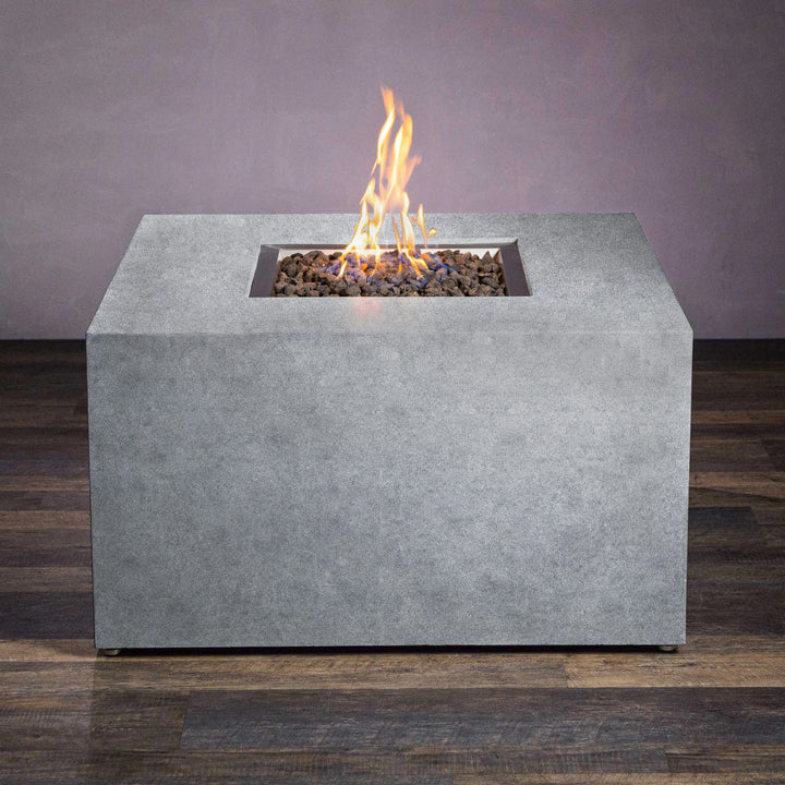 Front view of the Starfire Designs Beton 42" Natural Gray Square Gas Fire Pit showcasing a natural concrete finish with clean lines. This gas fire pit includes hidden propane tank storage and is designed to offer an elegant solution for backyard or patio spaces. The fire is enhanced by dark lava rocks, giving it a natural, sophisticated look.