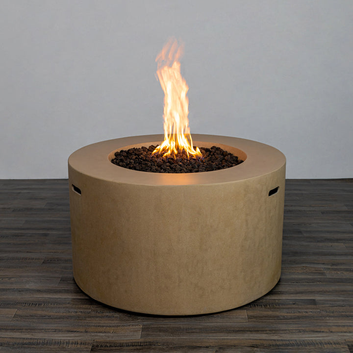 Front view of the Starfire Designs Beton 42" Sand Round Concrete Gas Fire Pit with a steady, bright flame glowing above the lava rocks. The sand-colored surface provides a modern yet natural appearance for any outdoor space. 