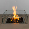 Close-up of the glowing flame on the Starfire Designs Beton 42-inch sand square gas fire pit. Includes a glass wind guard, black lava rocks, and hidden propane tank for modern outdoor fire pit enthusiasts.