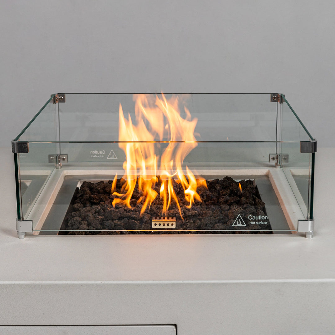 A close-up view of the lively flames burning within the Starfire Designs Beton 42" White Square Hidden Propane Tank Gas Fire Pit, surrounded by protective glass and filled with lava rocks.