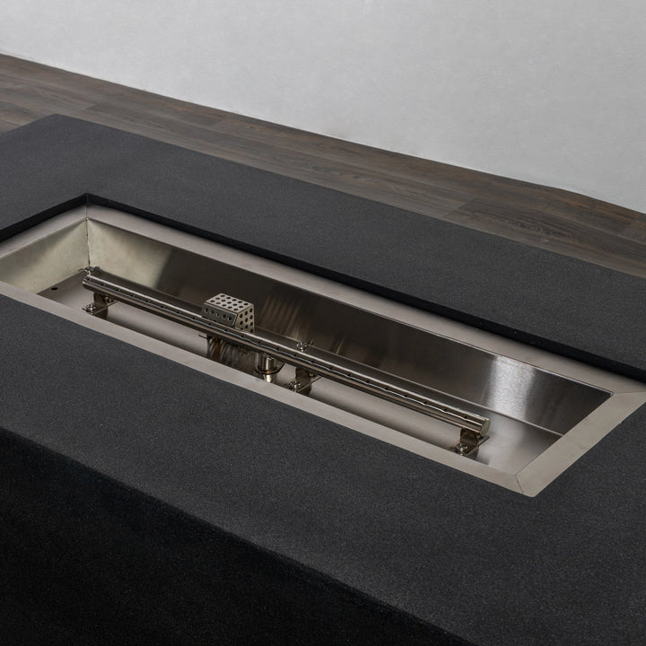 Detailed close-up of the stainless steel burner pan of the Starfire Designs Beton 55" Graphite Rectangle Gas Fire Pit, highlighting the linear burner with precise perforations for a consistent flame presentation.