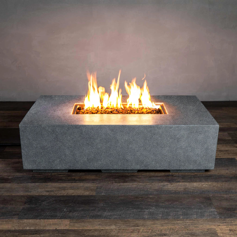 Front view of the Starfire Designs Beton 55" Graphite Rectangle Gas Fire Pit. The durable graphite concrete construction is paired with a rectangular firebox that houses a natural gas burner, surrounded by black lava rock media. Flames rise elegantly from the center, adding warmth and ambiance to any outdoor space.