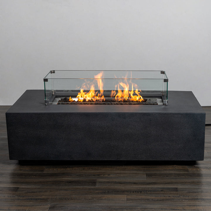 Close-up of the Starfire Designs Beton 55" Graphite Rectangle Gas Fire Pit featuring the tempered glass wind guard and linear flames glowing atop the burner, designed for wind protection and elegant outdoor enjoyment.