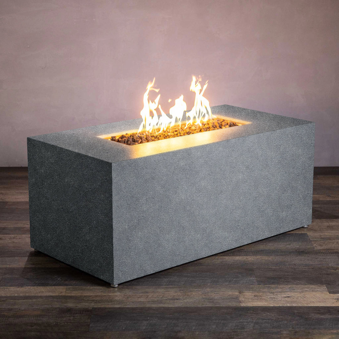 Angled view of the Starfire Designs Beton 55" Graphite Rectangle Hidden Propane Tank Gas Fire Pit, showcasing the modern concrete design with a smooth graphite finish and a robust flame in the rectangular burner filled with lava rock. Perfect for outdoor spaces, this gas fire pit offers both functionality and style with its hidden propane tank feature