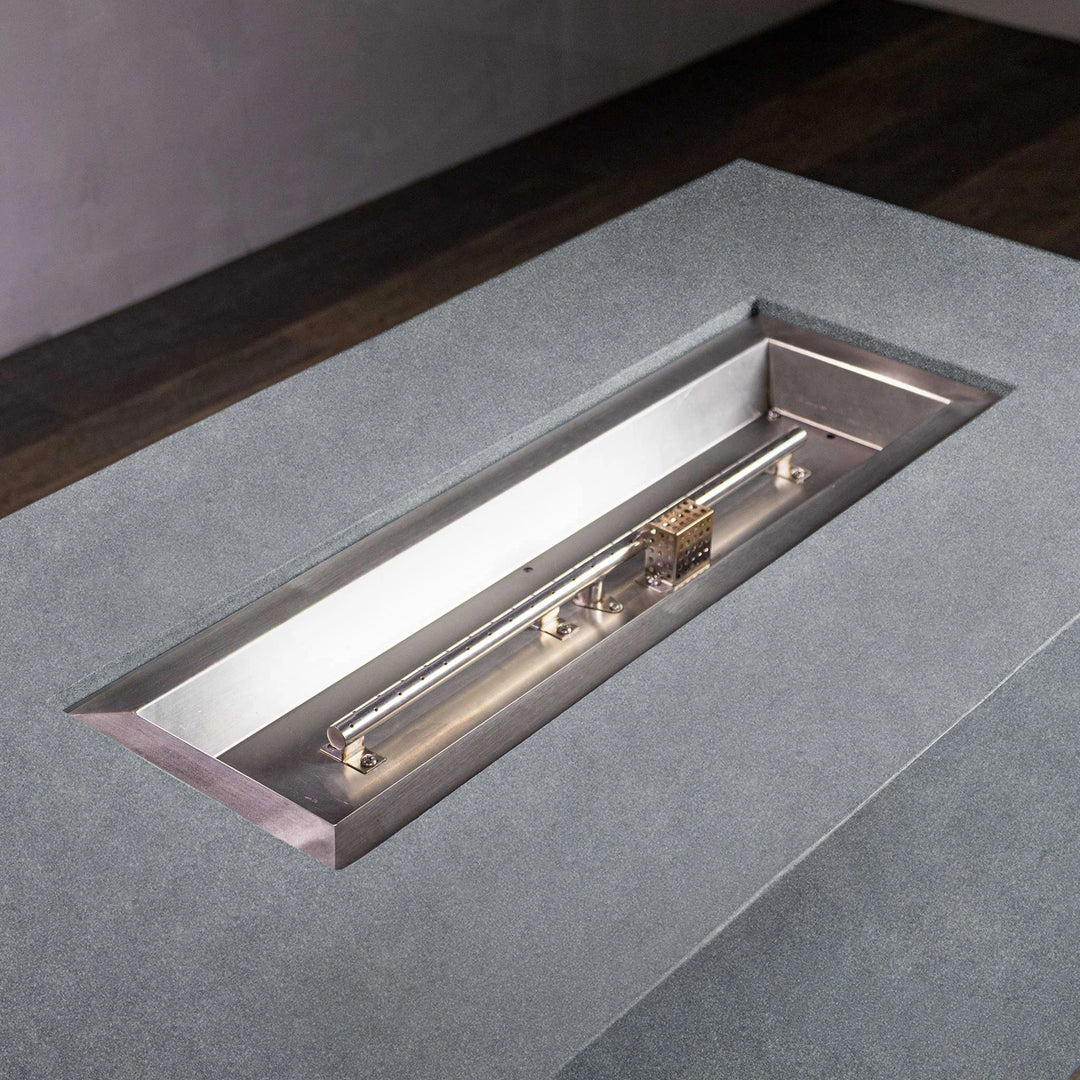 Top view of the stainless steel burner inside the Starfire Designs Beton 55" Graphite Rectangle Hidden Propane Tank Gas Fire Pit. The sleek design of the burner system is encased within a robust graphite concrete frame, ensuring both durability and modern aesthetics for outdoor living spaces