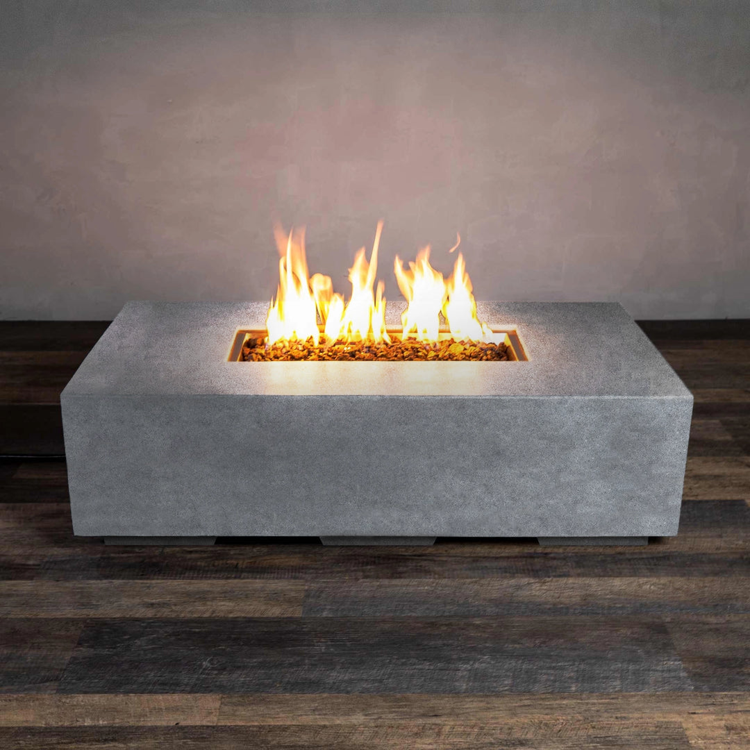 The Starfire Designs Beton 55" Natural Gray Rectangle Gas Fire Pit in action, presenting a powerful and consistent flame atop black lava rocks. The natural gray concrete construction offers a robust and weather-resistant frame that complements any outdoor decor. The fire pit’s rectangular shape creates a modern focal point for backyard gatherings.