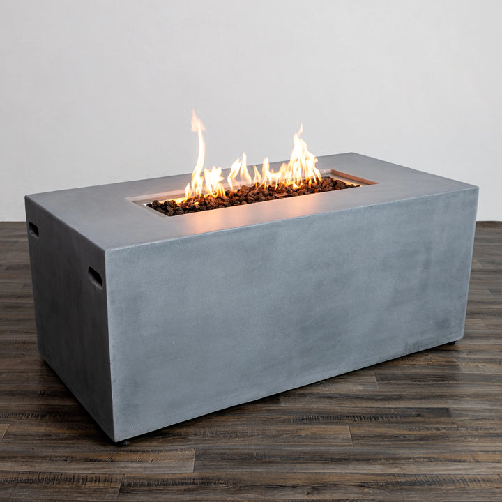 Angled view of the Starfire Designs Beton 55" Natural Gray Rectangle Hidden Propane Tank Gas Fire Pit with an active flame, showcasing the clean edges and soft gray hue of the concrete structure. Ideal for stylish backyard setups and outdoor fire pit gatherings.