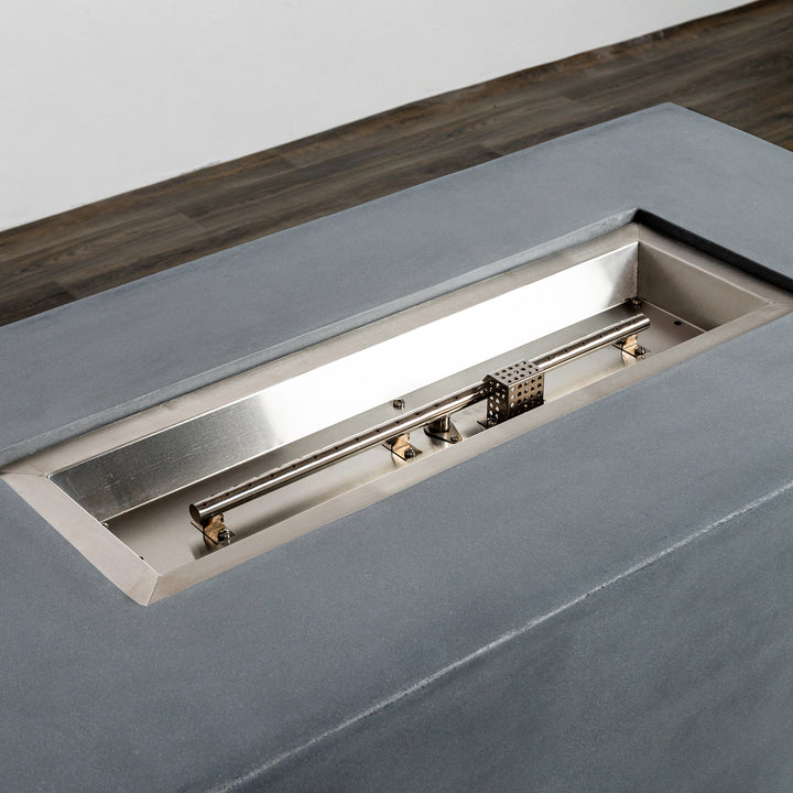 Top view showing the stainless-steel burner insert of the Starfire Designs Beton 55" Natural Gray Rectangle Hidden Propane Tank Gas Fire Pit. The sleek rectangular fire burner is crafted to deliver consistent flames, set within the minimalistic gray concrete fire pit design.