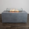 Full front view of the Starfire Designs Beton 55" Natural Gray Rectangle Hidden Propane Tank Gas Fire Pit with flames glowing inside the tempered glass wind guard. The glass enclosure enhances safety and adds elegance to the modern fire pit design, perfect for outdoor entertaining.