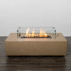 Starfire Designs Beton 55-inch sand rectangle gas fire pit lit with bright flames enclosed by a glass wind guard. The fire pit creates a stunning focal point, combining warmth and style for outdoor living spaces.