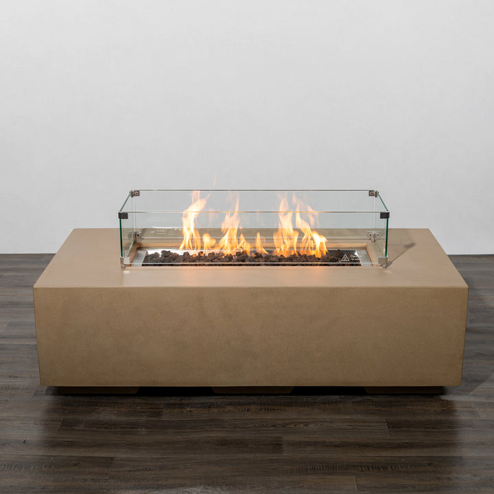 Starfire Designs Beton 55-inch sand rectangle gas fire pit lit with bright flames enclosed by a glass wind guard. The fire pit creates a stunning focal point, combining warmth and style for outdoor living spaces.