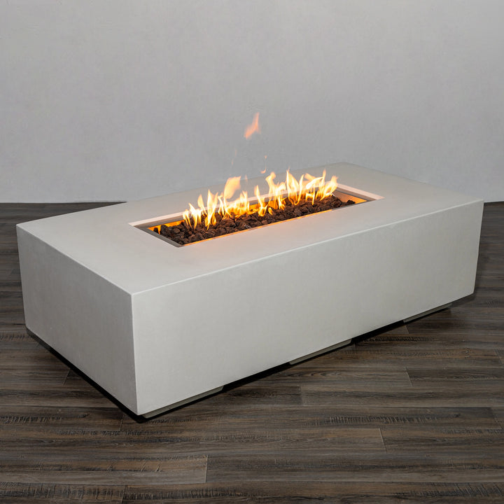 Side view of the Starfire Designs Beton 55" White Rectangle Gas Fire Pit with flames burning over black lava rocks. The long, rectangular burner creates a stunning linear fire effect, enhancing any outdoor ambiance. 