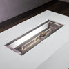 Detailed view of the stainless steel burner of the Starfire Designs Beton 55" White Rectangle Hidden Propane Tank Gas Fire Pit, highlighting the high-quality construction. The white concrete exterior enhances the sleek and modern design, ideal for high-end outdoor fire pit installations.