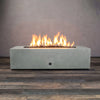 Lit natural gray 60x24 inch rectangular concrete gas fire pit, perfect for creating a warm and inviting atmosphere in your outdoor patio or backyard