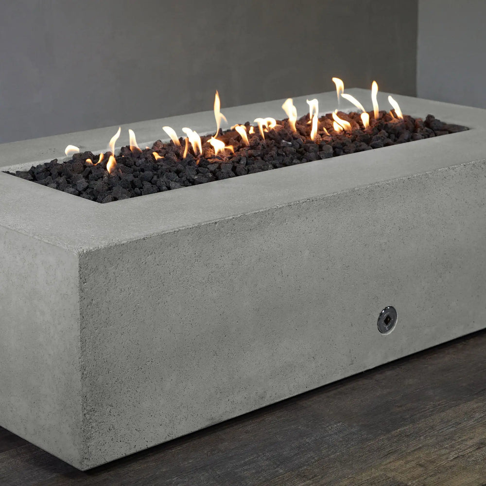 Starfire Designs Concrete Rustic Gravity Gas Fire Pit in natural gray with the burner turned off. This 60-inch by 32-inch fire pit displays a smooth rectangular concrete finish, ideal for creating a sophisticated outdoor ambiance. It is equipped with an easy-access propane door and is suited for commercial and residential use