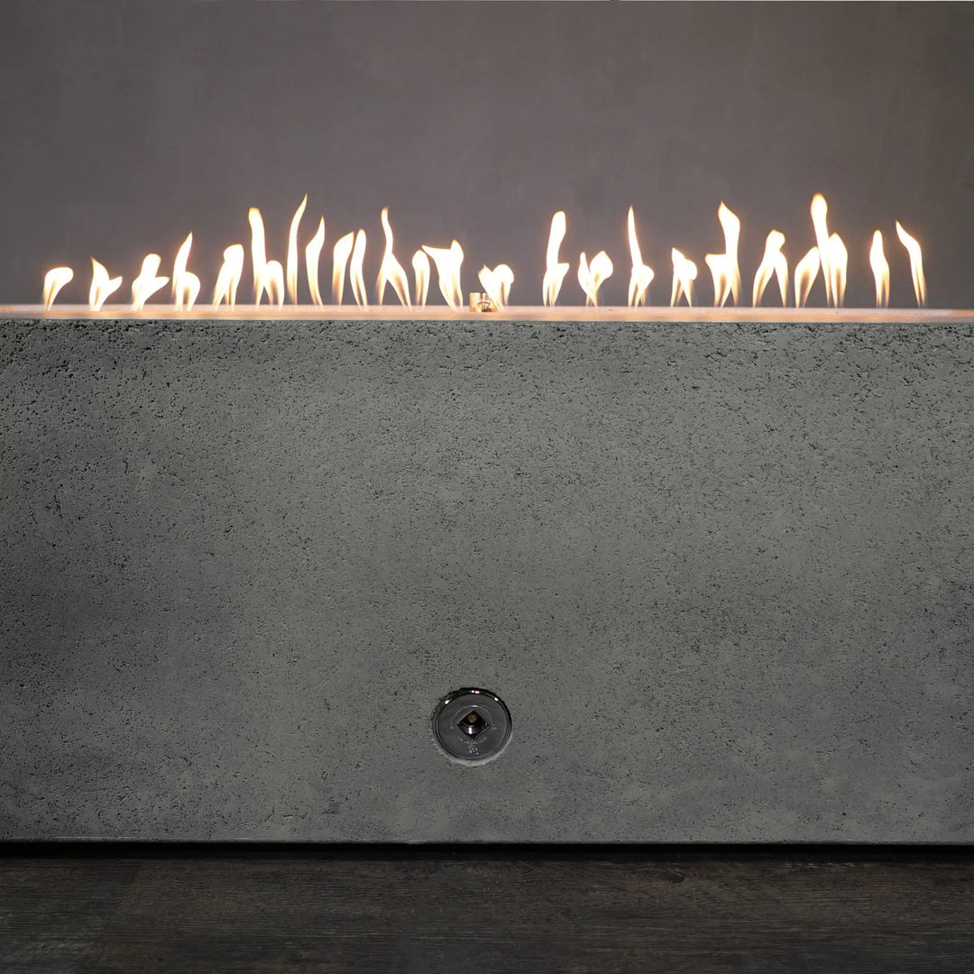 Starfire Designs Concrete Rustic Gravity Gas Fire Pit in natural gray, 60" x 32", with flames burning along the stainless steel burner. The long rectangular shape and smooth concrete finish bring a modern yet rustic feel to any outdoor area. The dancing flames provide a warm and inviting atmosphere. Best for residential and commercial outdoor use