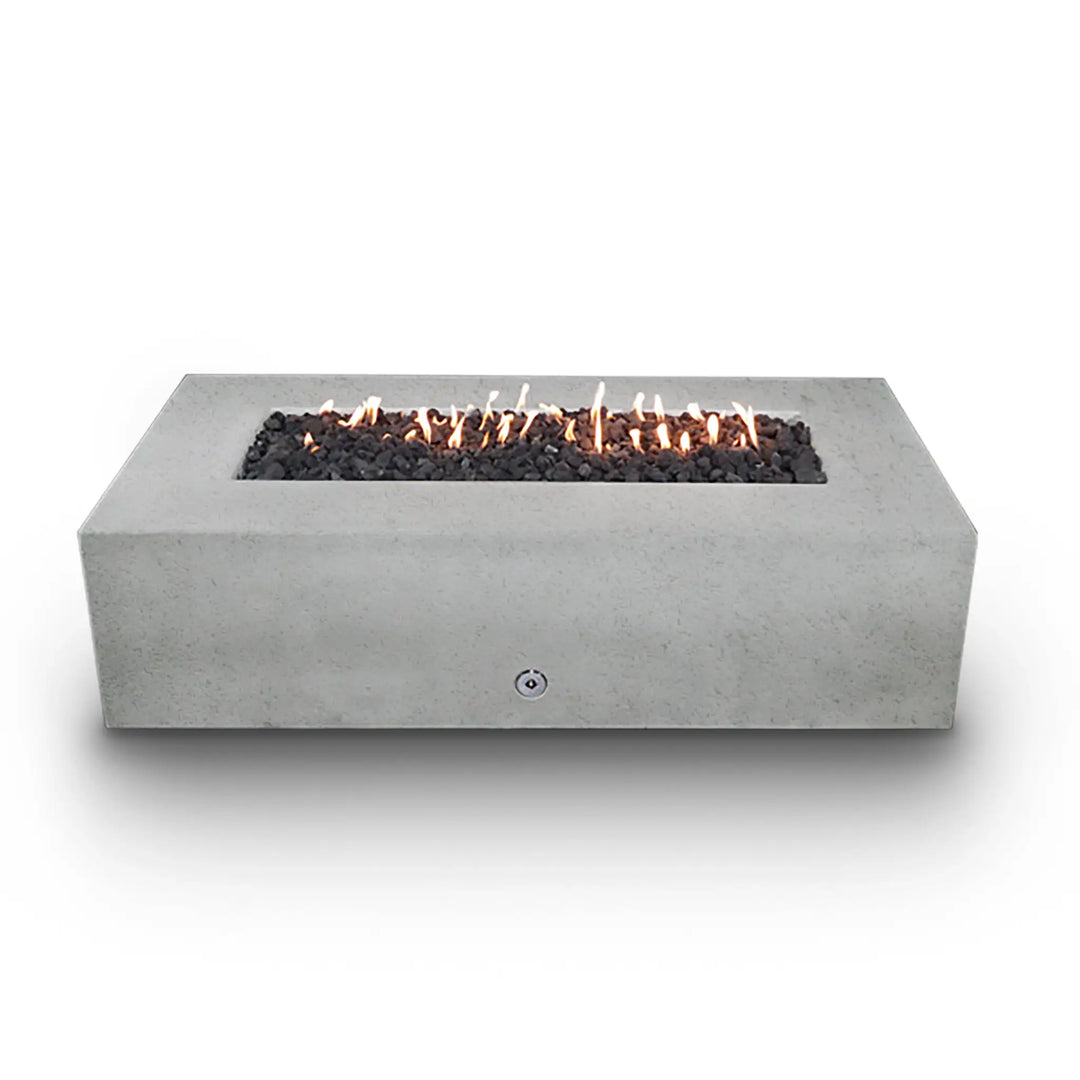 Starfire Designs Concrete Rustic 60-inch by 32-inch Rectangle Gravity Gas Fire Pit in White, filled with black lava rocks and a steady flame. The durable white concrete construction offers a stunning contrast to the dark rocks, making it a perfect luxury addition to any outdoor living space. This fire pit provides both visual appeal and functional outdoor heating